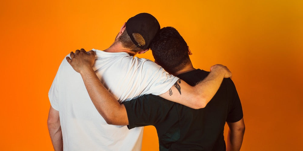 Two men facing away from the camera with arms over each others' shoulders