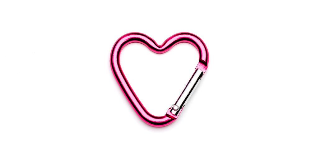 A pink carabiner in the shape of a heart on a white background