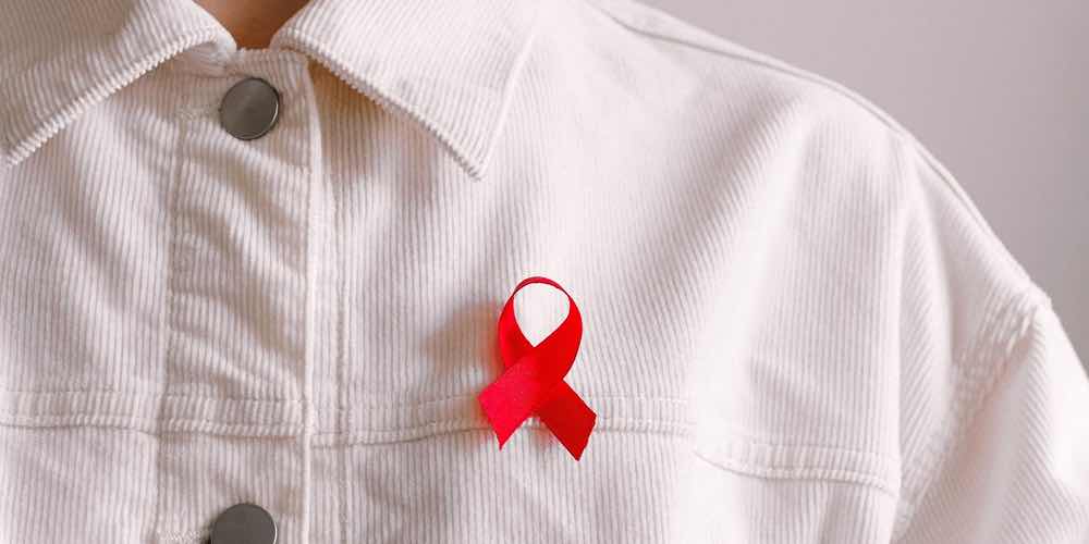 A red AIDS ribbon on a white denim jacket