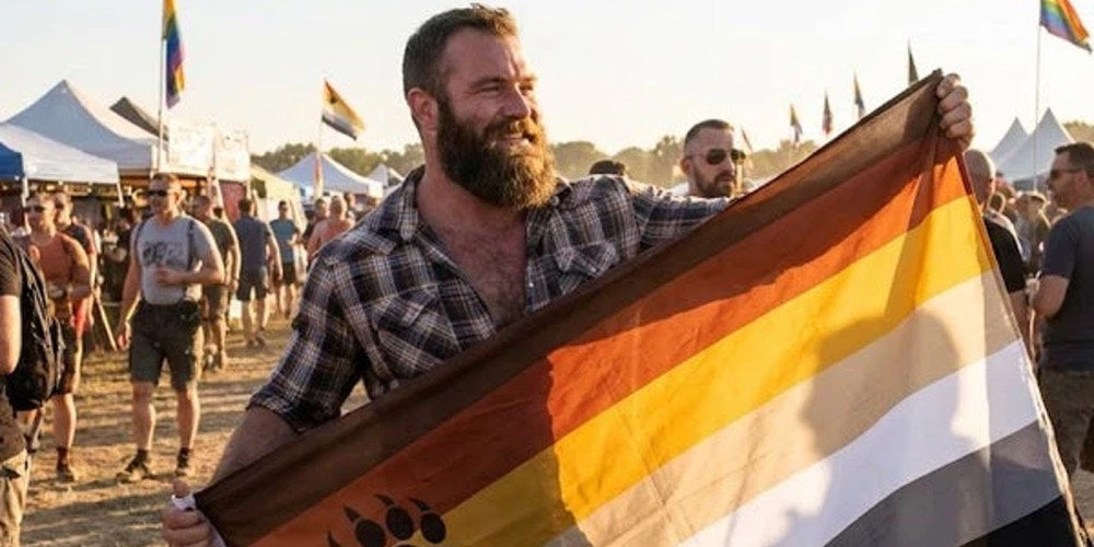 Bearded man at a festival holding the bear pride flag