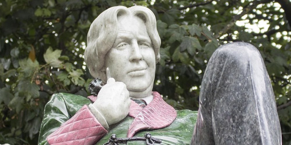A photograph of a sculpture of Oscar Wilde touching his green carnation, a monument in Dublin