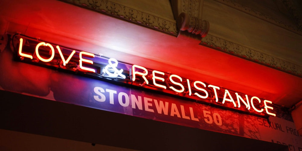 Neon sign spelling out LOVE & RESISTANCE, with Stonewall 50 writing below