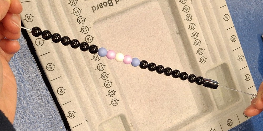 Hands holding a partially made beaded bracelet