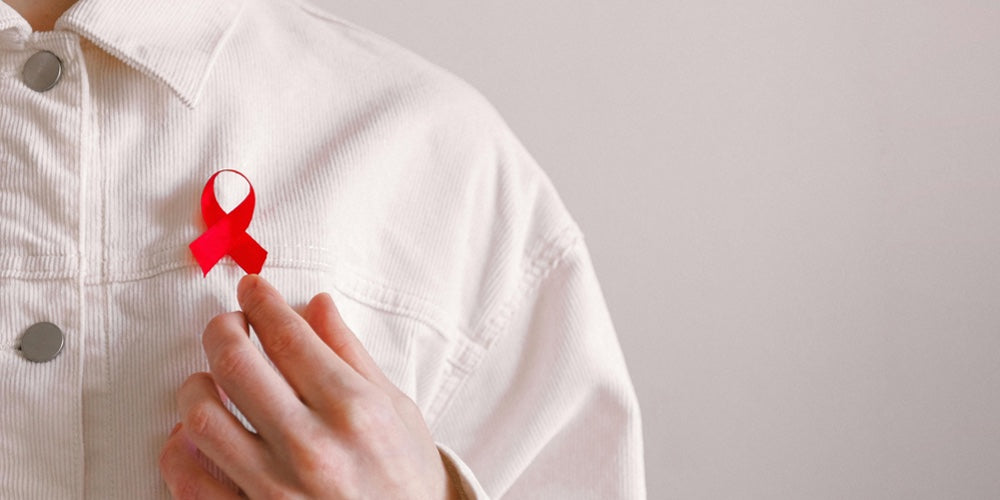 A red AIDS ribbon worn on a white denim jacket