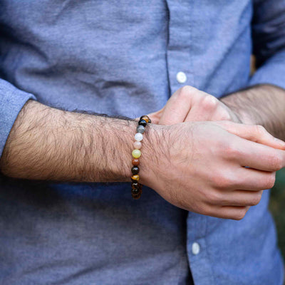 Semi-precious bear pride bracelet worn on a wrist, showing natural earth-toned gemstones
