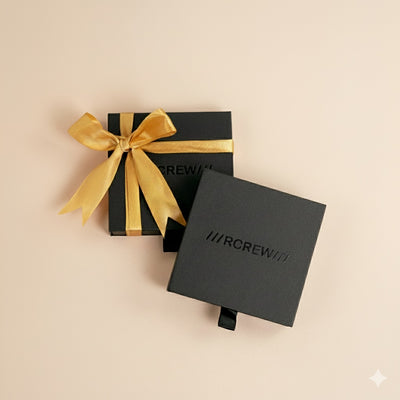 Black gift box with gold ribbon and 'RCREW' branding on a beige background