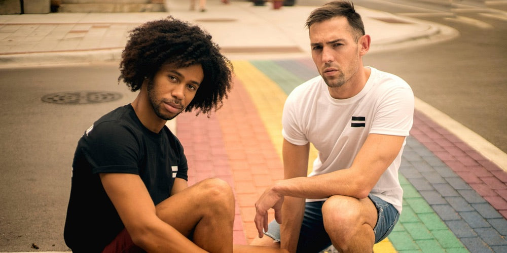 Two men kneeling down on a rainbow crossing/walkway